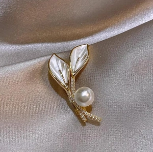 Élégante broche feuille en nacre avec perle et cristaux sur un fond de soie douce