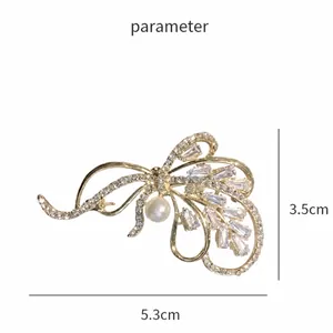 Élégante broche nœud dorée avec cristaux et perle, dimensions de 5,3 cm x 3,5 cm