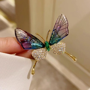 Makrodetail der Schmetterlingsbrosche aus Acryl mit Goldbasis und glitzernden Flügeln