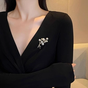Elegante spilla di perle a spiga con foglie dorate e cristalli su abito nero