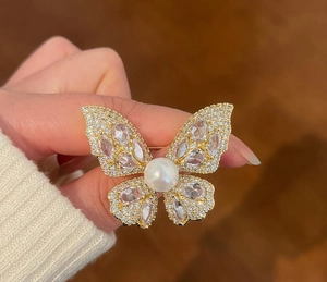 Detail shot of luxury butterfly brooch with sparkling zircon and large white pearl