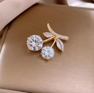 Macro detail of cherry brooch featuring sparkling clear crystal fruits and gold leaves