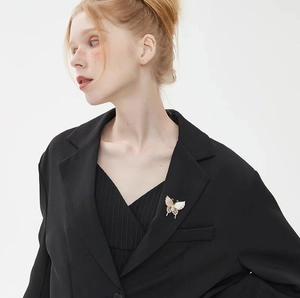 Elegante broche de mariposa vintage francés con nácar rosa en una americana negra de moda