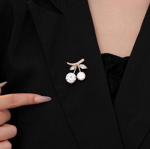 Elegant gold cherry brooch with sparkling rhinestones pinned on a black blazer suit