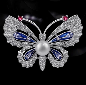 Détail macro de la broche papillon avec perle, émail bleu et pierres de zircon brillants