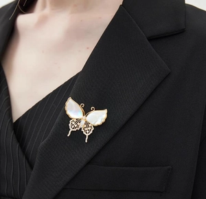 Primer plano de un broche de mariposa vintage con nácar y cristales en una chaqueta