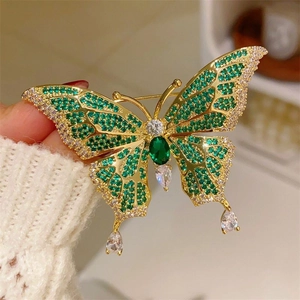 Detail of emerald butterfly brooch with teardrop crystals on a white sweater