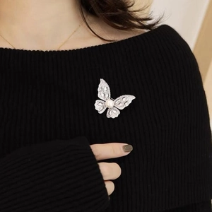 Sparkling silver butterfly brooch with rhinestones and pearl on black sweater