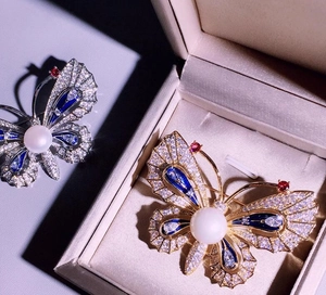 Détails de broche papillon avec ailes serties de zircon et une grande perle blanche centrale