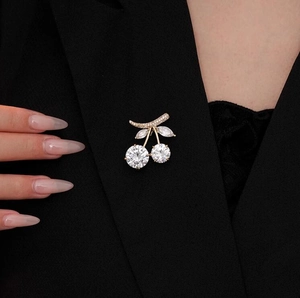 Detail of elegant cherry brooch with crystals pinned on a classic black suit lapel