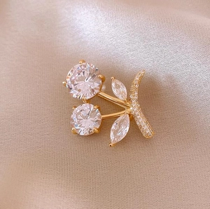 Exquisite cherry brooch with crystal rhinestones on elegant champagne silk fabric background