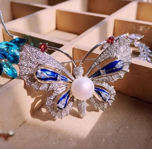 Détail macro de broche papillon avec perle blanche, émail bleu et zircons brillants