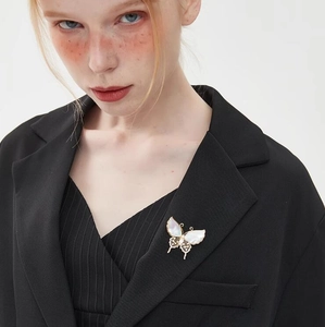 Detalle de un broche de mariposa vintage francés con nácar sobre una solapa negra