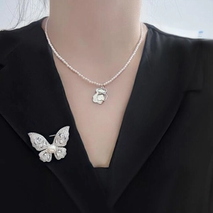 Luxury butterfly brooch with sparkling crystals and pearl necklace on a black suit jacket