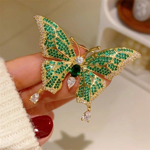 Detail of a gold butterfly brooch with emerald green gemstones and pear-shaped drops