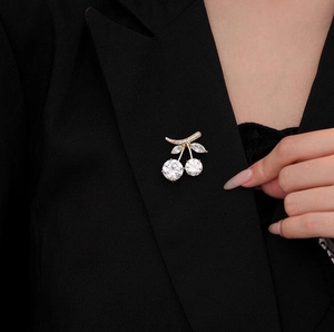 Detailed close-up of a sparkling cherry brooch pinned on a black suit lapel