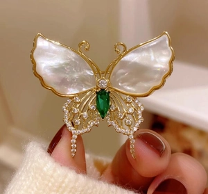 Primer plano detallado de un broche de mariposa vintage francés con nácar y gema verde brillante