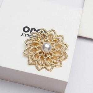 Macro de la broche fleur ajourée dorée avec perles blanches et strass étincelants