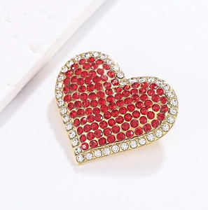 Detailed view of heart brooch with red rhinestones and gold plating finish