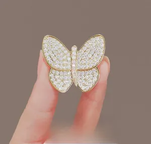 Detail shot of golden butterfly brooch with sparkling rhinestones held in hand