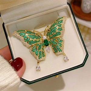 Detailed view of butterfly brooch with emerald gems, sparkling crystals and teardrop charms
