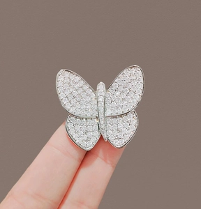 Macro detail of butterfly brooch with sparkling white zircons held by hand to show size
