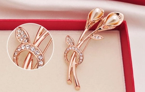 Macro detail of rose gold Calla Lily brooch with faux pearls and white rhinestones