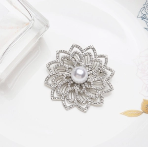 Broche fleur argentée avec perle centrale et pétales en cristal sur fond sophistiqué