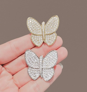 Close-up of golden and silver butterfly brooches with sparkling pave-set zircons