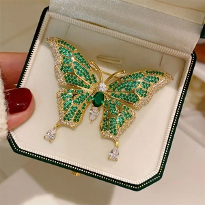 Detailed macro view of vintage butterfly brooch with green emerald gems and crystal accents