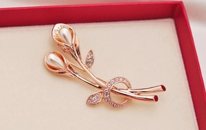 Macro detail of rose gold calla lily brooch with white pearls and sparkling rhinestones