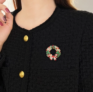 Détail de la broche couronne de Noël sur un manteau en tweed avec des strass brillants
