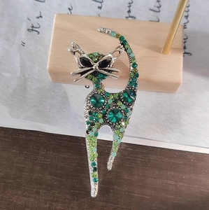 Cat shaped brooch with green crystals on vintage wood background for suits and coats