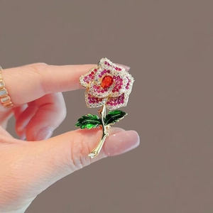 Elegant gold-tone metal rose brooch with red rhinestones and green enamel leaf accents