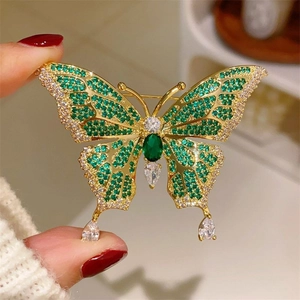 Macro detail of butterfly brooch with emerald crystals and gold metal finish