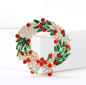 Détail d'une broche couronne de Noël dorée avec émail vert et cristaux étincelants