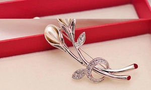 Detail of silver tulip brooch with faux pearls and crystals in a red jewelry box