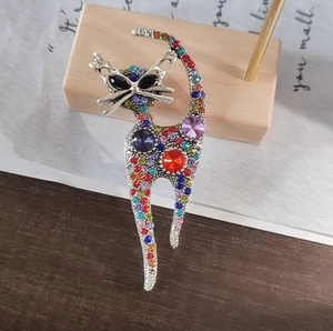 Elegant cat brooch pin with colorful rhinestones on a wooden stand for suits