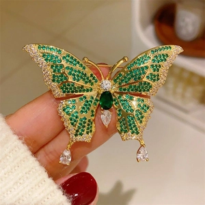 Macro detail of butterfly brooch with emerald green crystals and hanging teardrop charms