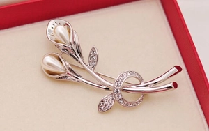 Macro shot of silver tulip brooch with white pearls and sparkling rhinestones in a gift box