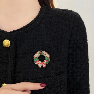 Détail d'une broche couronne de Noël scintillante sur une veste en tweed noir