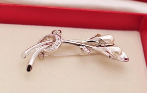 Macro detail of silver tulip brooch with white pearls and sparkling zircons in a gift box