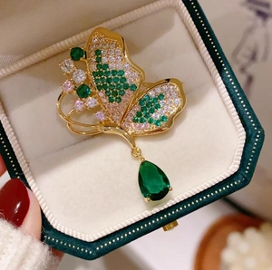 Spilla a farfalla dorata con cristalli verde smeraldo e ciondolo in gemma a forma di pera