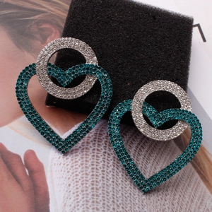Detail view of heart and circle drop earrings featuring deep teal and white crystals