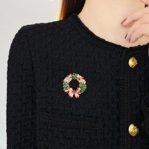 Broche couronne de Noël avec émail et strass portée sur une veste en tweed