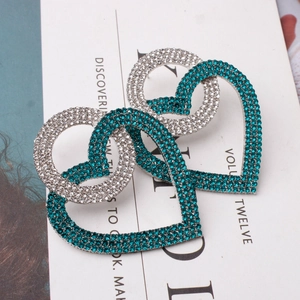 Close-up of double heart earrings with white and teal rhinestones on 925 silver needles