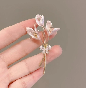 Gros plan détaillé de la broche calla en émail rose avec un nœud en strass brillant