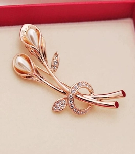 Macro shot of rose gold Calla Lily brooch with pearls and crystals on jewelry box