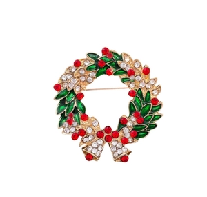 Vue détaillée de la broche couronne de Noël avec strass rouges et émail vert sur alliage doré