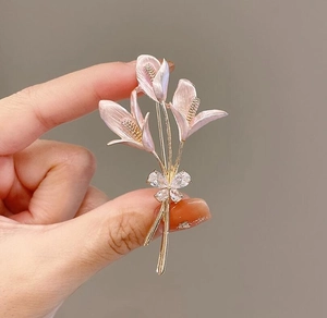Détail d'une broche lys rose avec placage d'or et nœud en cristaux scintillants